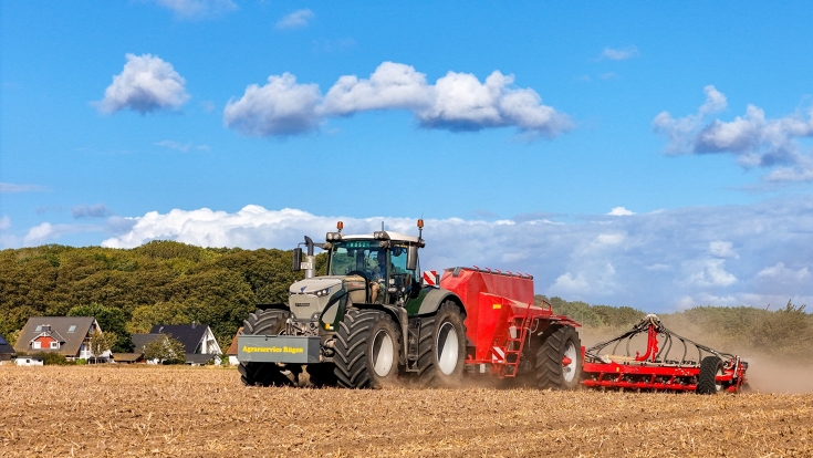 Ein Fendt 900 Vario in der Farbe Tannengrün fährt auf einem Stoppelfeld.