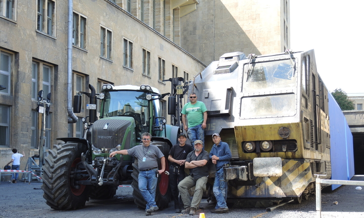 Fünf Männer stehen stolz vor einem Fendt 900 Vario, im Hintergrund eine alte Lagerhalle