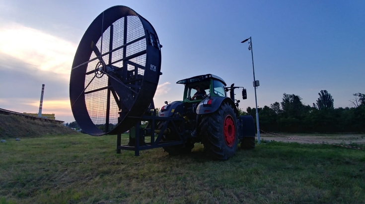 Ein Fendt 939 Vario steht mit einer riesigen Windmaschine auf einer Wiese.