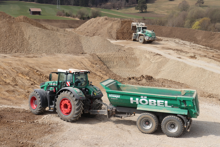 Fendt 306 Vario mit Krampe-Kipper im Einsatz auf einer Baustelle bzw. Kiesgrube, während im Hintergrund ein Radlader Schüttgut bewegt.