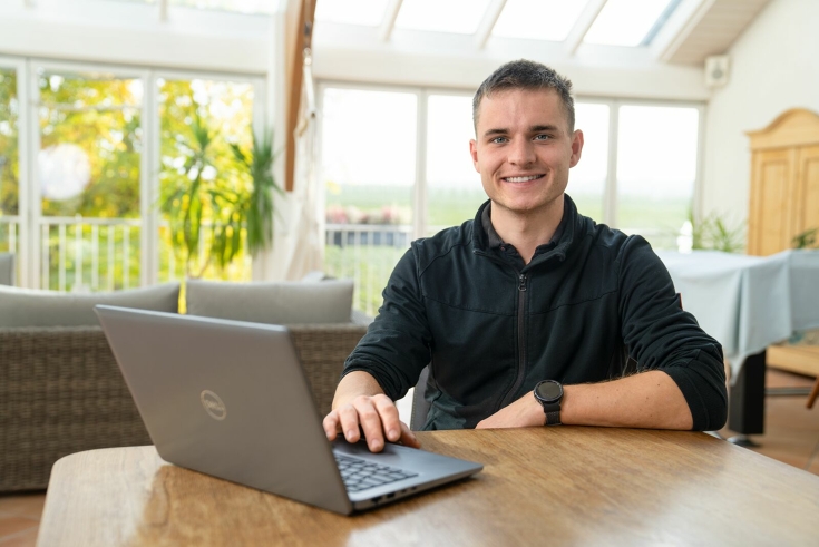Tobias Händel sidder ved bordet og ser ind i kameraet. Foran står hans bærbare computer, som han arbejder på.
