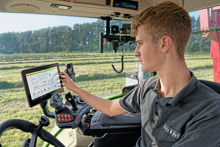Manuel Kleinhans sits in the cab of the Fendt Vario. He operates the FendtOne terminal, which is installed in the cab.