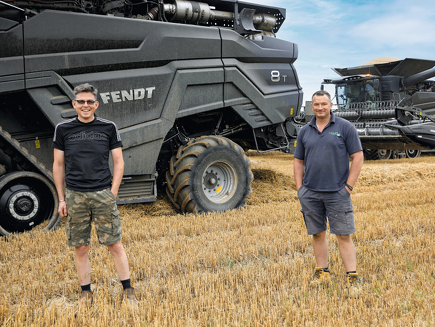 Ben Walkers and Alex Robinson stand in front of their Fendt IDEAL8 combines.