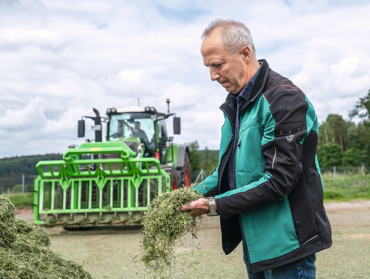 Thoralf Müller stands at the silo and inspects silage in his hands