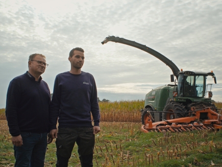 Michael et Dirk Bredehöft se tiennent dans un champ avec une Fendt Katana vert en arrière-plan.