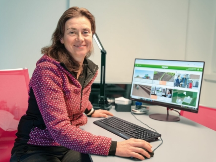 Elisa Gregorat est assise à son bureau devant son ordinateur. Elle regarde la caméra.