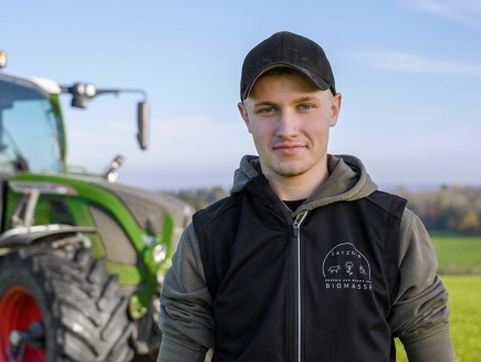 Tim Satzger se tient devant un tracteur Fendt vert avec des jantes rouges.