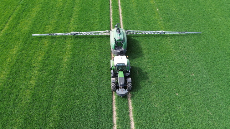 Riprese effettuate da un drone che mostrano un Fendt 620 Vario verde con un Rogator trainato mentre lavora nei campi